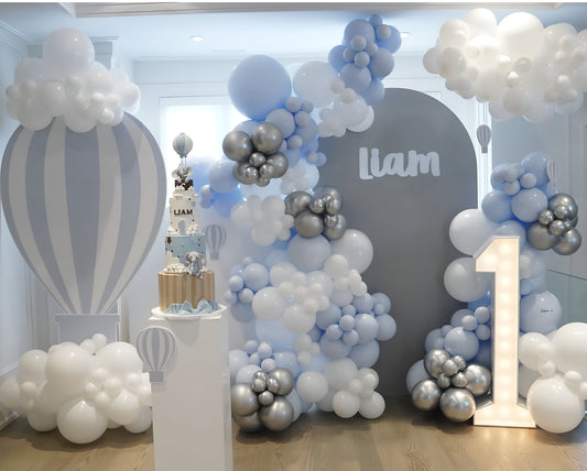 Blue and white hot air balloon themed balloon backdrop with clouds and marquee number one for a first birthday celebration in Toronto.