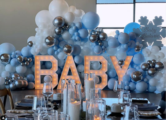 Baby shower balloon backdrop in blue, white, and silver with marquee BABY letters and elegant table setting