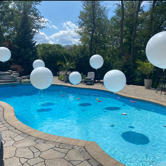 Modern pool party with large white floating balloons and tropical decor in Toronto backyard