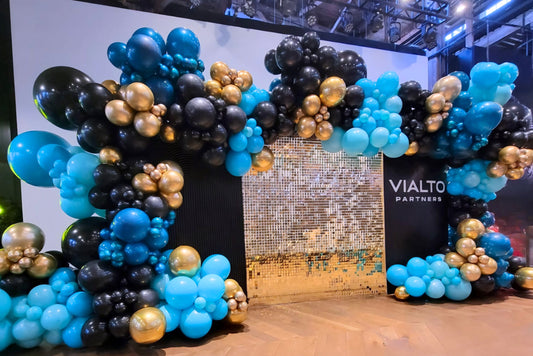 Shimmer wall with two balloon garlands in teal, black, and gold creating a full backdrop for corporate event with Vialto Partners