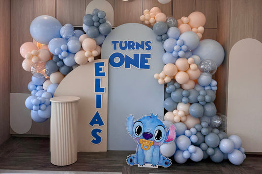 Custom light blue and peach organic balloon backdrop with a Lilo and Stitch cutout for a boy's first birthday party in Toronto.