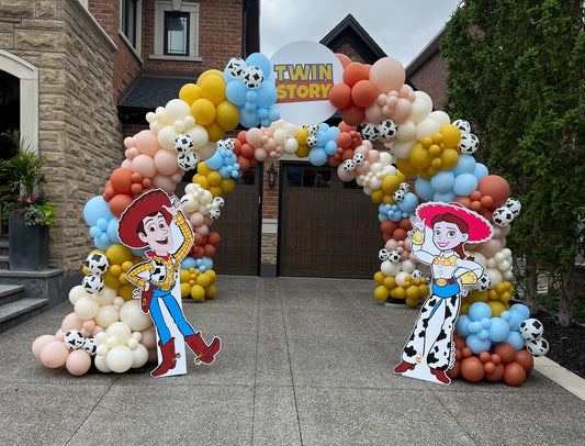 Twin Story - Toy Story themed balloon arch with cow print balloons, Woody and Jessie cutouts for twin birthday celebration