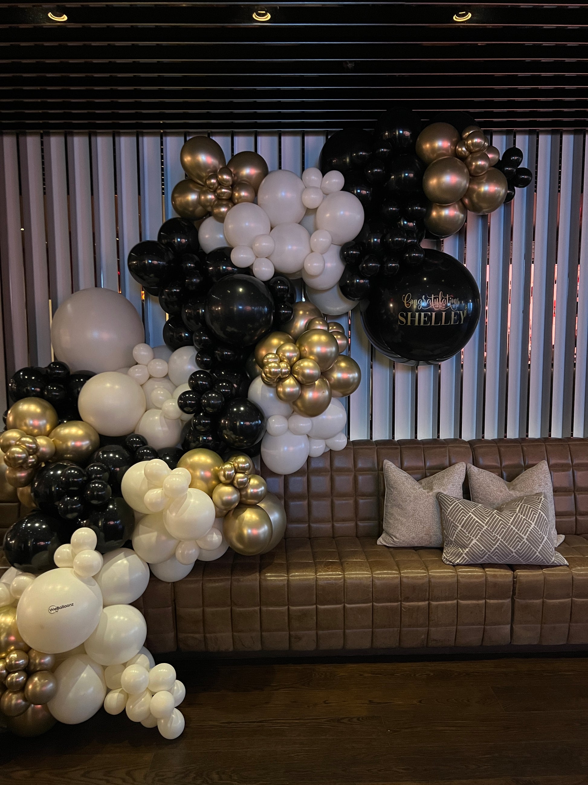 Elegant black, gold, and white balloon garland installed at a Toronto restaurant for a corporate farewell celebration.