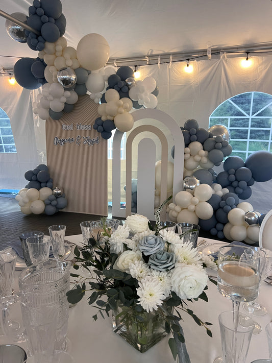 Dusty blue, sand, and slate grey organic balloon installation for a luxury tented baptism with custom arched backdrops and floral centerpieces by WeBalloonz.