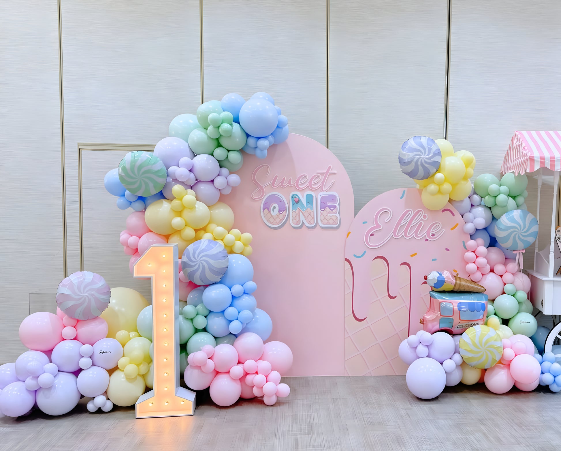 Sweet One pastel balloon backdrop with candy and ice cream theme, featuring soft pink, yellow, and blue balloons for a first birthday celebration in Toronto