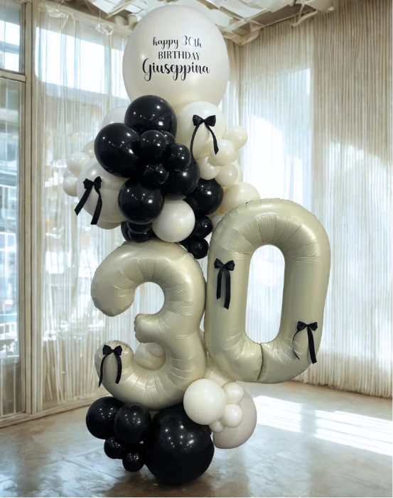Elegant black and white 30th birthday balloon tower with personalized topper and metallic number balloons.