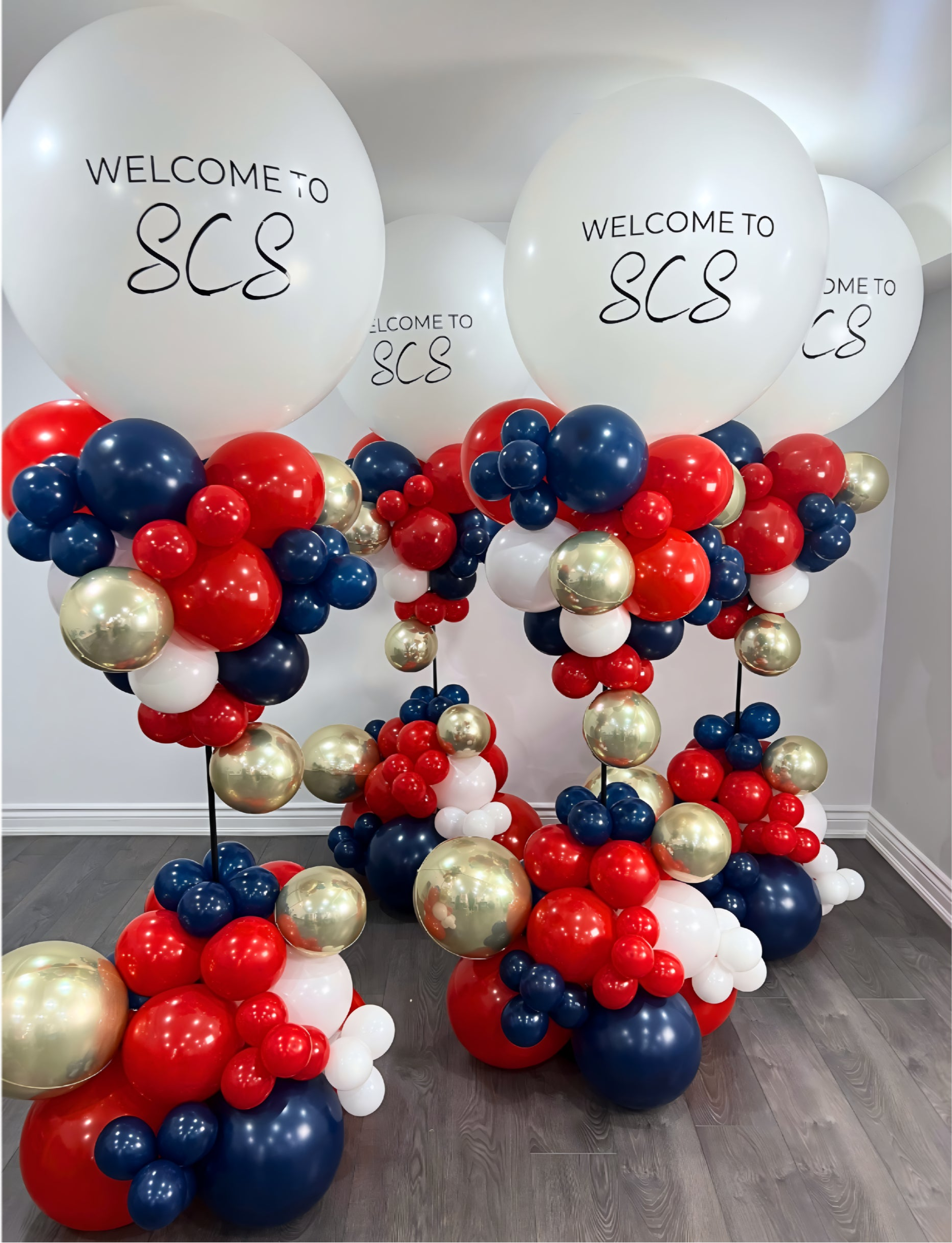 Corporate balloon towers in red, navy, white, and gold with custom welcome balloons for company event