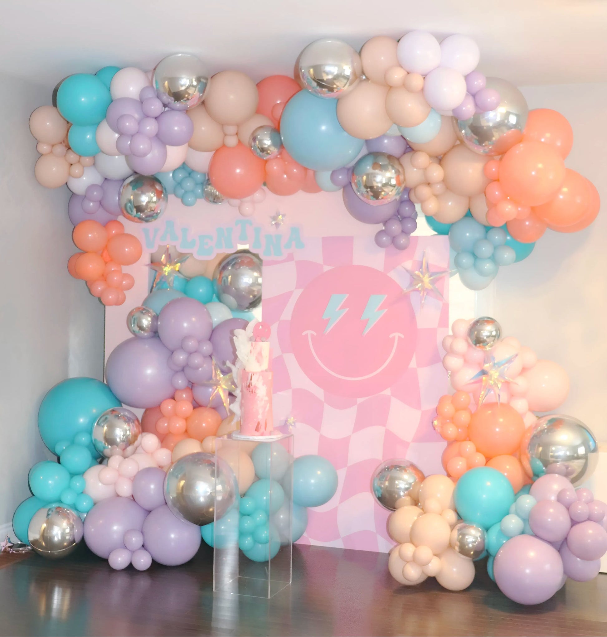 Custom pastel balloon preppy backdrop with pink checkered backdrop, silver balloons, and personalized name “Valentina” for a fun birthday celebration