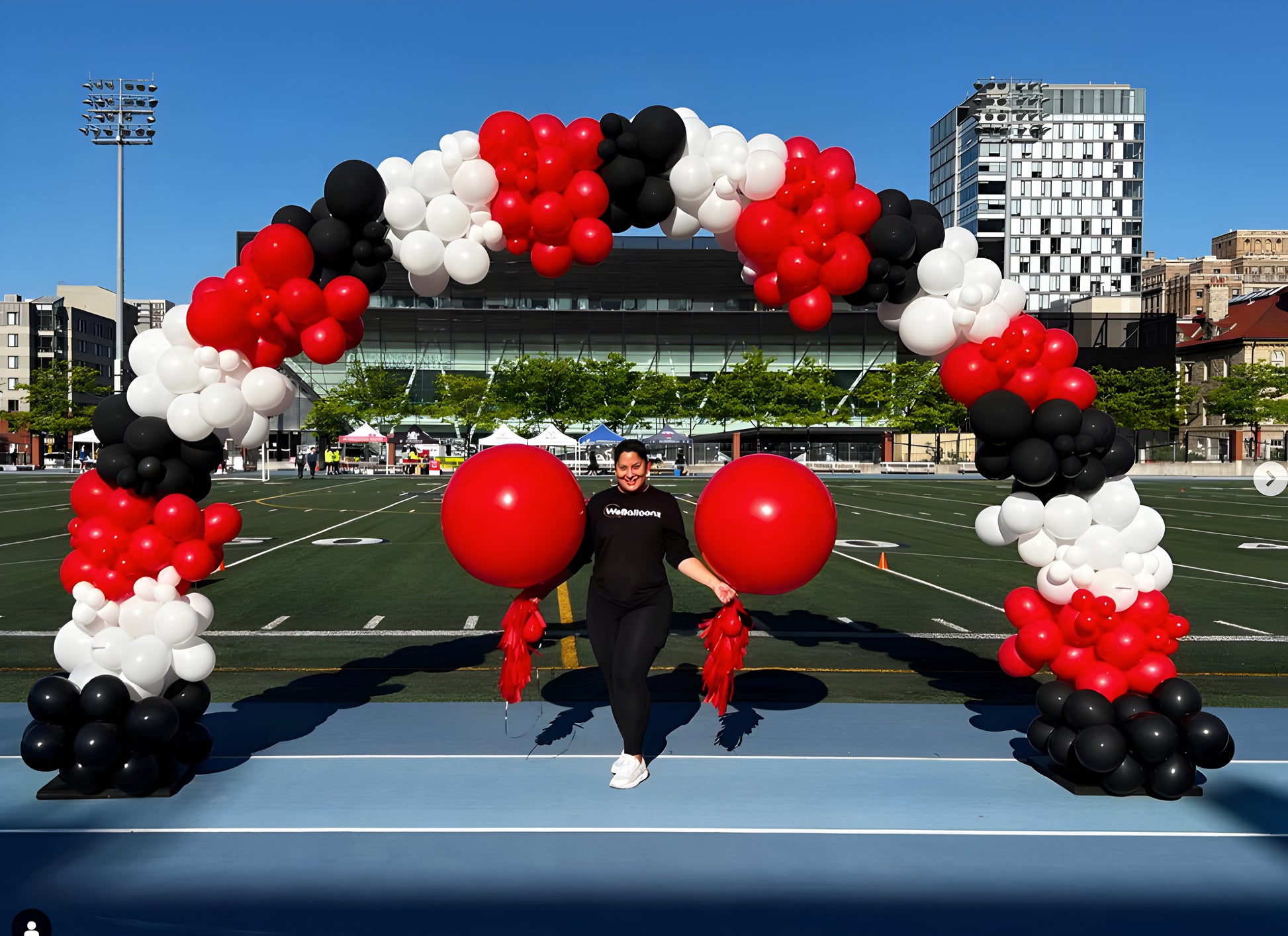 Large red, black, and white balloon arch with jumbo balloons at a stadium entrance, perfect for school spirit, sports events, and corporate celebrations