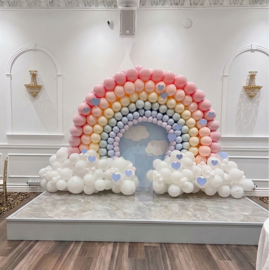 A massive 12ft wide luxury pastel rainbow balloon arch installation featuring high-density clouds for a professional event backdrop in Vaughan by WeBalloonz