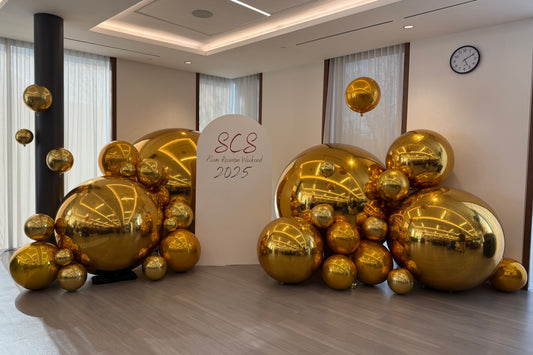 Gold chrome balloon backdrop with custom signage for SCS Alumni Reunion Weekend 2025, indoor event decor setup