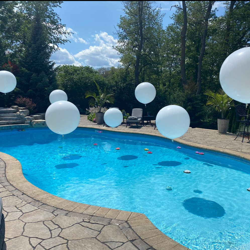 Modern pool party with large white floating balloons and tropical decor in Toronto backyard