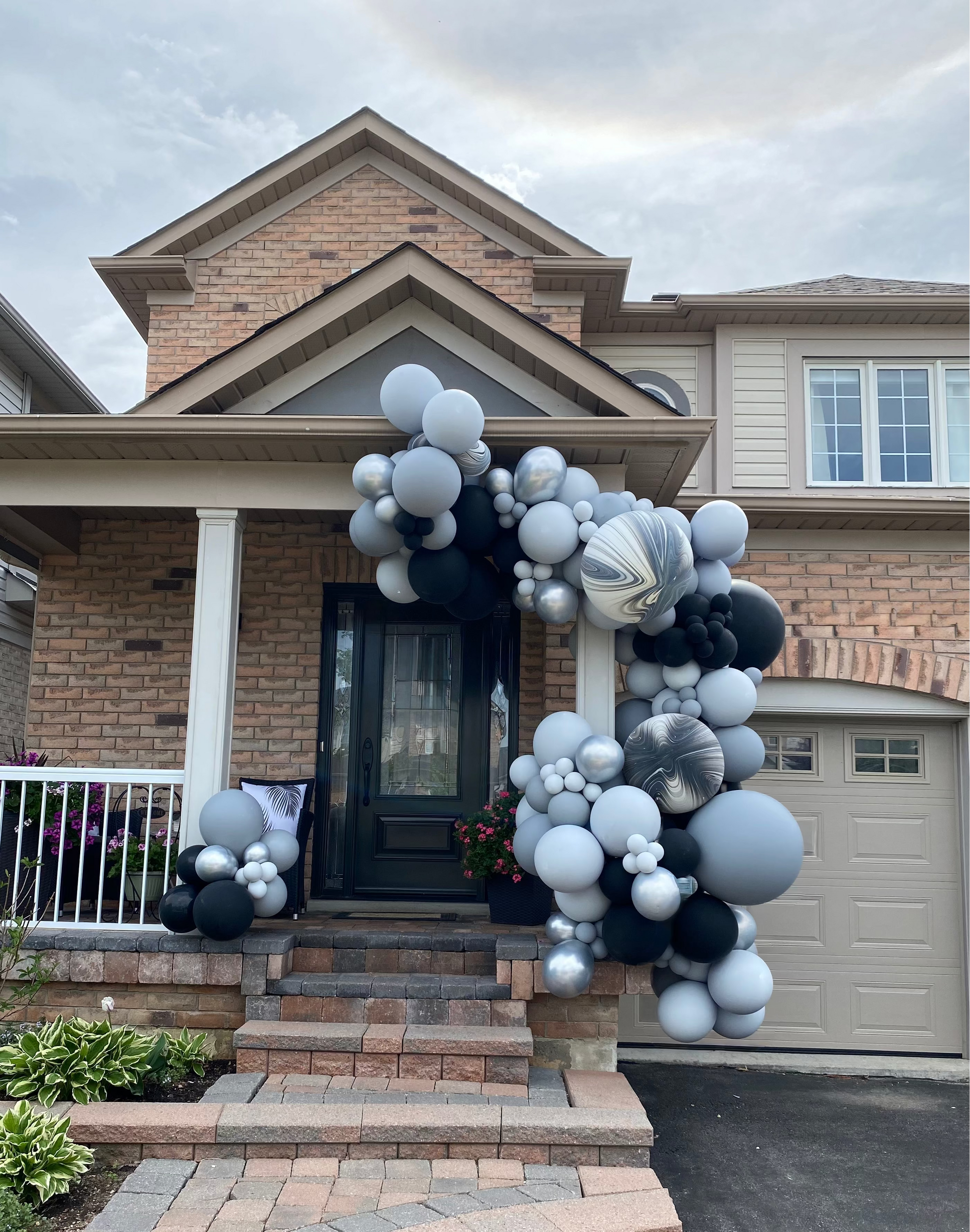 A 16ft luxury monochrome graduation balloon garland in black, grey, and marble, custom-installed around a residential porch entrance in King City by WeBalloonz.