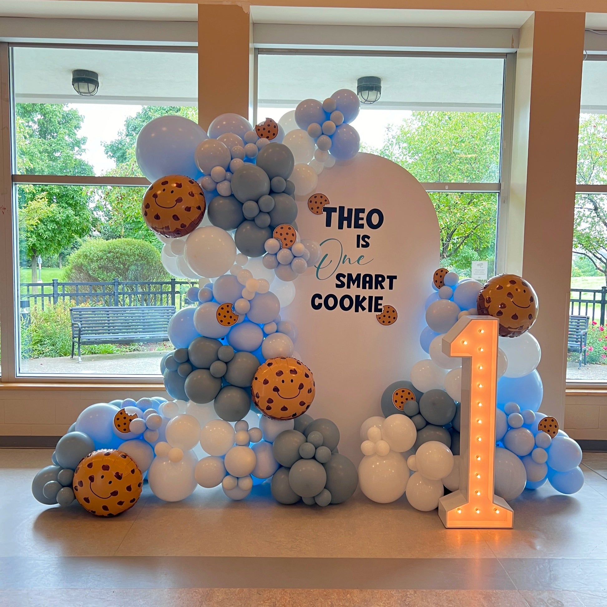 One Smart Cookie themed balloon garland with custom backdrop and light-up marquee number — perfect for a first birthday celebration