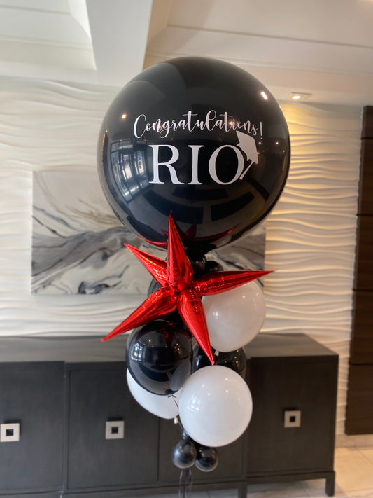 Personalized black and white graduation helium bouquet with a red metallic star and custom Contratulations 'RIO' message by WeBalloonz.