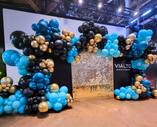 Shimmer wall with two balloon garlands in teal, black, and gold creating a full backdrop for corporate event with Vialto Partners