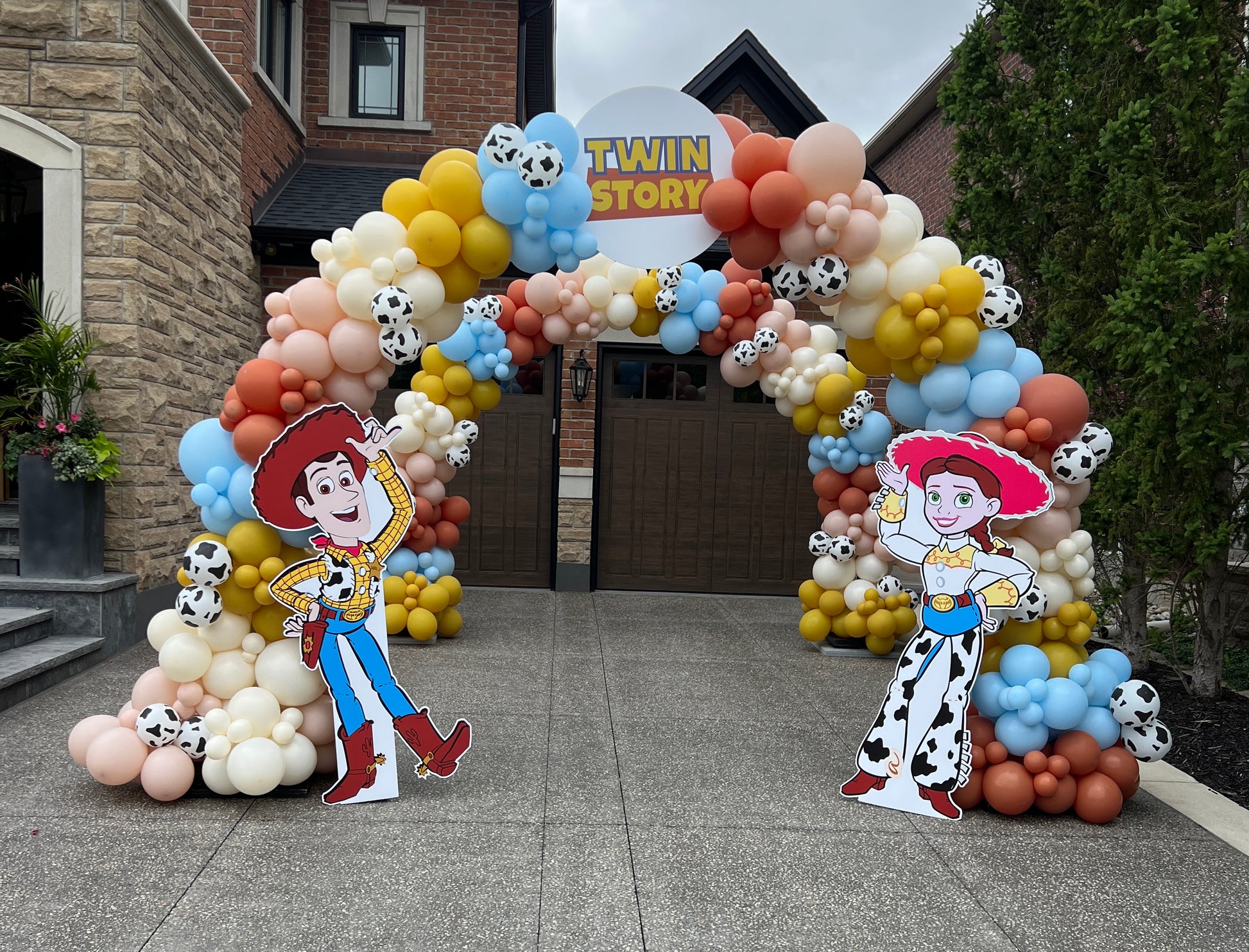 Twin Story - Toy  Story themed balloon arch with cow print balloons, Woody and Jessie cutouts for twin birthday celebration