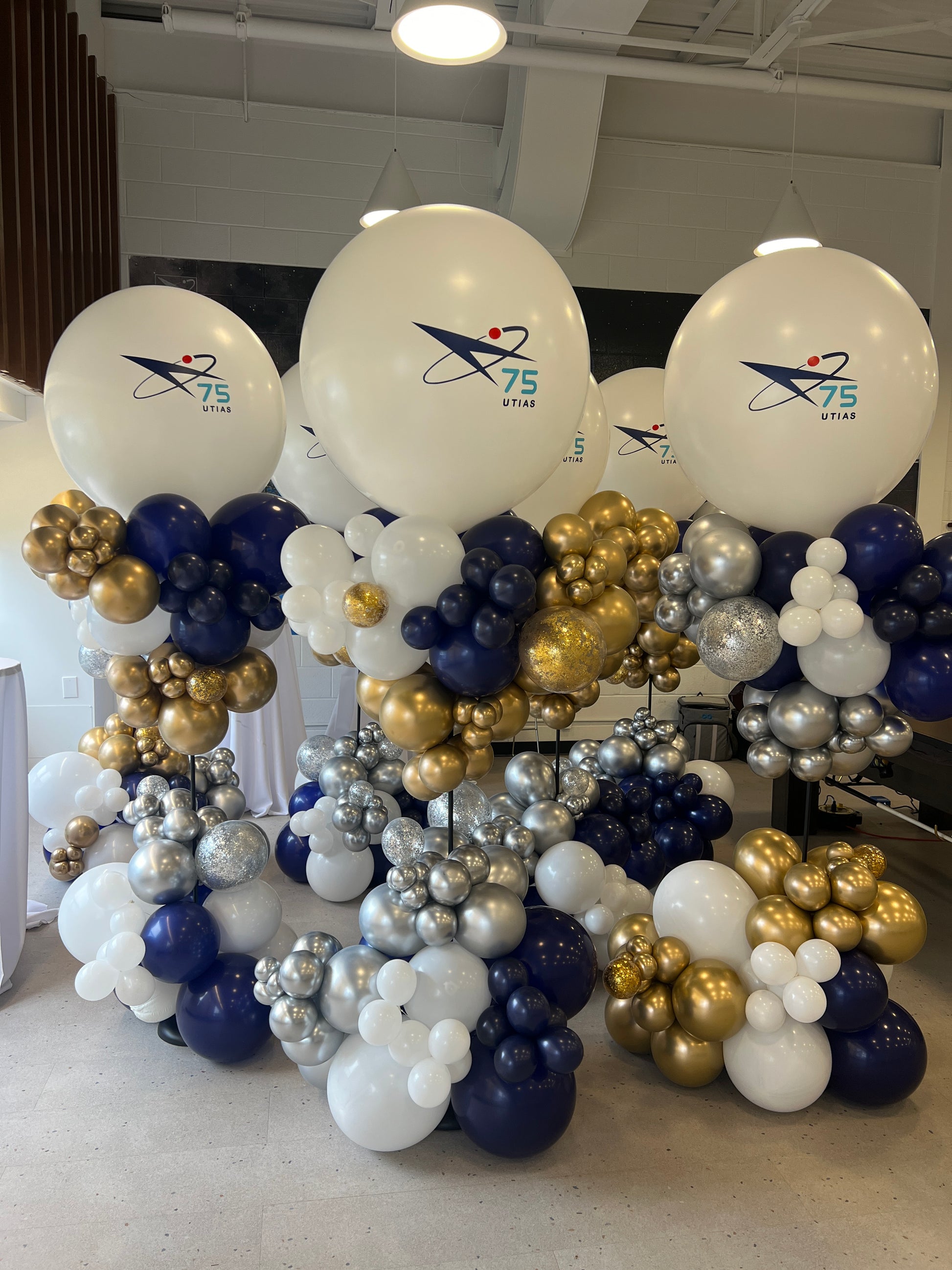 Professional 7ft tall navy, gold, and silver organic balloon towers featuring the University of Toronto UTIAS 75th Anniversary logo on jumbo focal balloons by WeBalloonz.