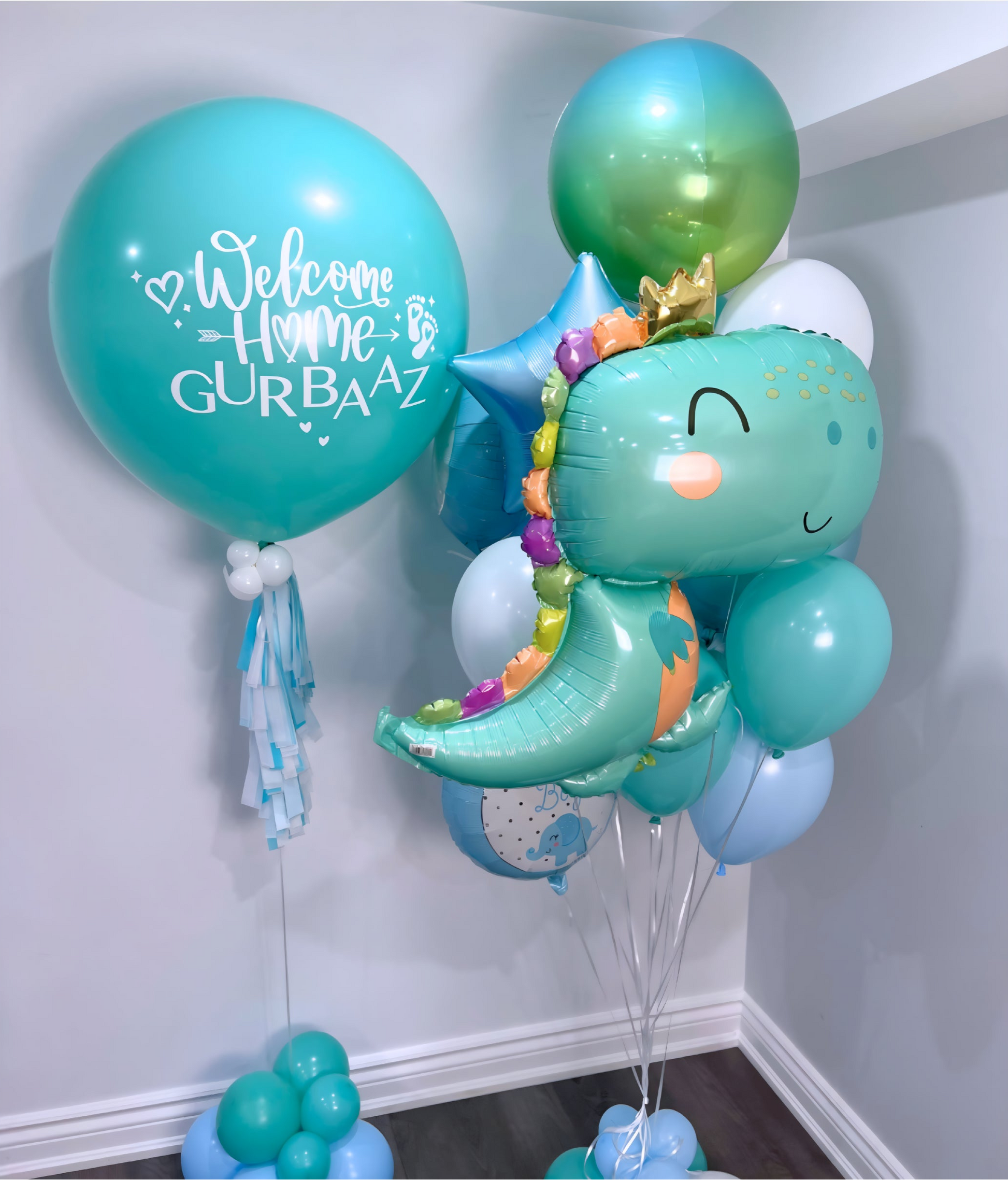 Welcome home helium balloon bouquet with teal personalized jumbo balloon and adorable dinosaur foil balloon.